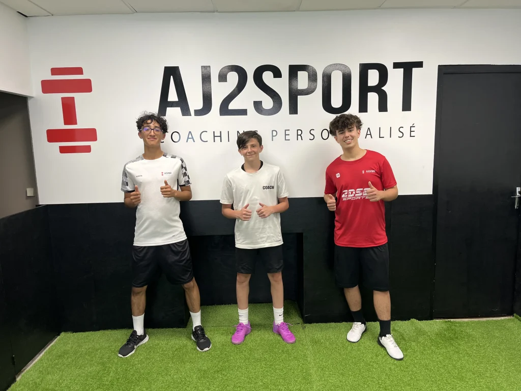 Trois jeunes joueurs de l'académie AJ2Sport souriant avec les pouces levés après l'entraînement