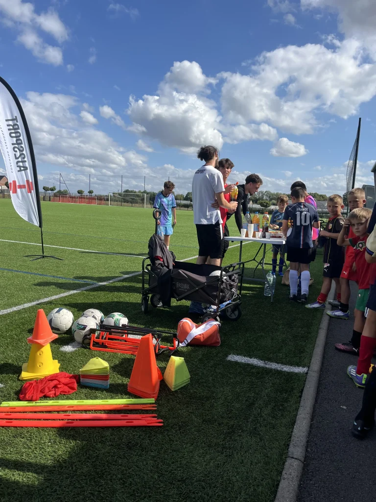 Jeunes footballeurs et coachs AJ2Sport partageant une collation au bord du terrain lors d'une pause