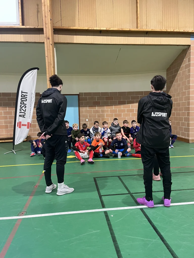 Coachs AJ2Sport donnant des instructions à un groupe de jeunes footballeurs lors d'un entraînement